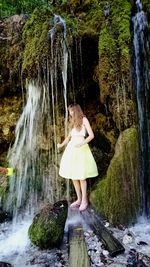 Full length of woman standing on rock in forest