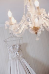 Close-up of chandelier hanging against dress at home