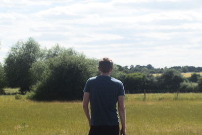 Rear view of man standing on field against sky