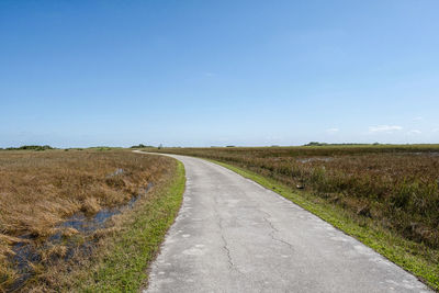 Road amidst field against sky