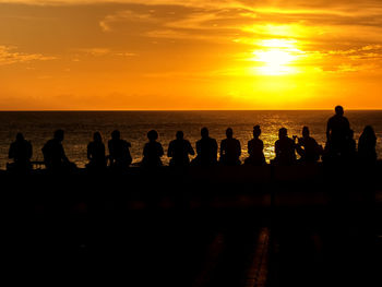 Silhouette people on beach against sky during sunset