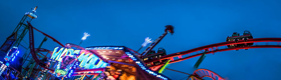 Low angle view of illuminated ferris wheel against blue sky