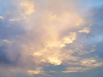 Low angle view of sunlight streaming through clouds