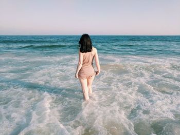 Rear view of man standing in sea against clear sky