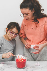 Two girls roast marshmallows over a candle fire.