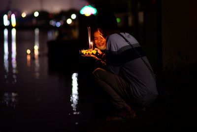 Young couple holding flowers with incense by river