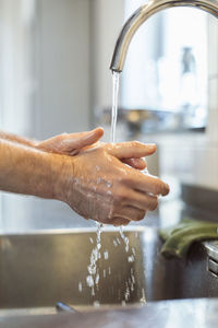 Cropped image of man washing hands in kitchen sink