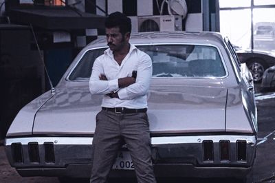 Full length portrait of young man standing in car