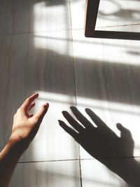 Cropped image of hand on tiled floor against wall