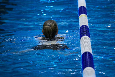 Rear view of woman swimming in pool