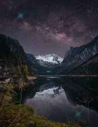 Scenic view of lake and mountains against sky at night