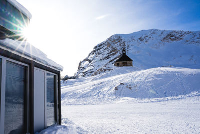 House on snowcapped mountain against sky