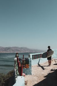 Rear view of boys looking at sea against clear sky