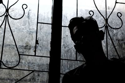 Portrait of silhouette man standing by window