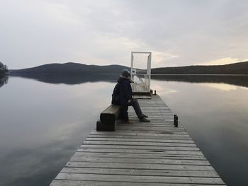 Man on pier at lake against sky