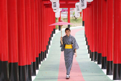 Portrait of woman with red umbrella walking in row