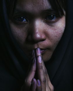 Close-up portrait of woman against black background