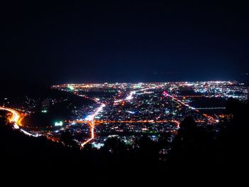 Illuminated cityscape against sky at night