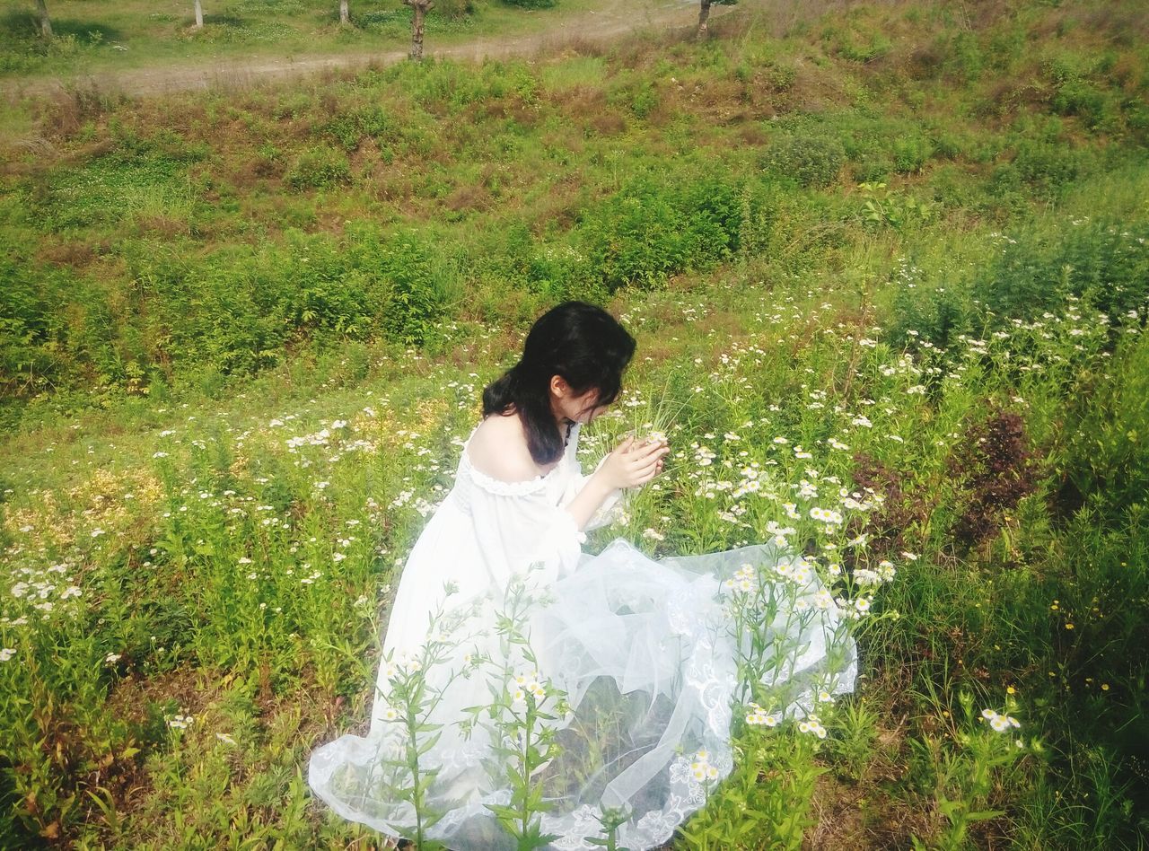 lifestyles, grass, leisure activity, standing, plant, casual clothing, three quarter length, green color, field, growth, nature, person, young adult, full length, high angle view, waist up, day, outdoors