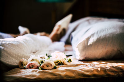 Low section of woman with flowers on bed at home