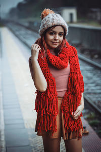 Portrait of young woman standing against wall during winter