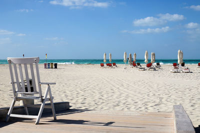 An empty beach near abu dhabi with turquoise water and umbrellas