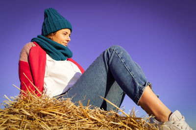 Low angle view of woman wearing hat against blue sky