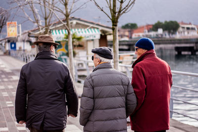 Rear view of friends wearing warm clothing while walking on street in city