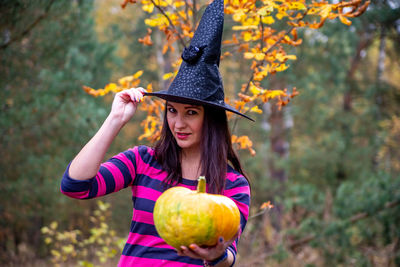 Woman in a witch costume with a pumpkin in the forest. background happy halloween holiday