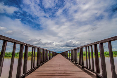 Footbridge leading towards bridge against sky