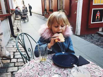 Cute girl eating food at sidewalk cafe