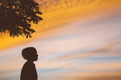 Silhouette girl against cloudy sky during sunset