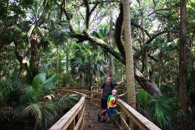 Man and boy on walkway through forest