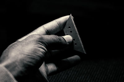 Close-up of person holding cigarette over black background