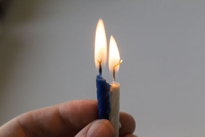 Close-up of hand holding illuminated candle