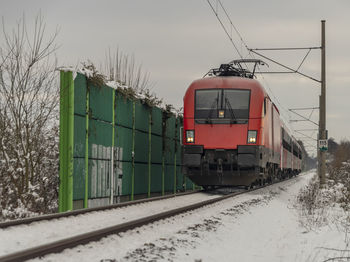 Train on snow covered railroad track against sky