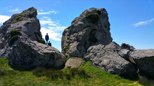 Woman climbing the cliff rocks by the ocean hiking trail