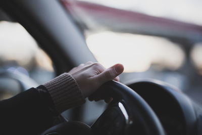 Cropped hand of man holding steering wheel