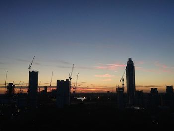 Silhouette of city against sky at dusk