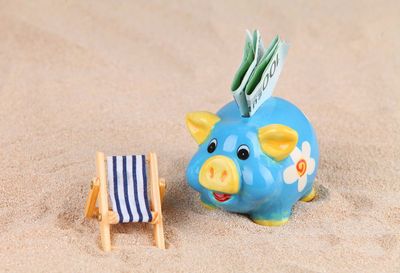 Close-up of piggy bank with paper currencies on sand