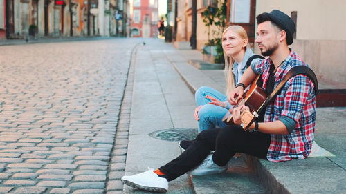 Young couple kissing on footpath in city