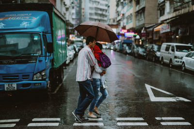 Man standing on wet street in city during monsoon