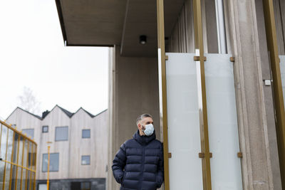 Man wearing face mask standing near building