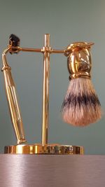 Close-up of shaving brush and razor on stand against wall
