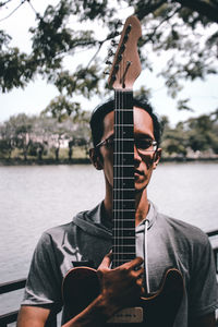 Portrait of man playing guitar by river