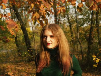 Portrait of smiling young woman in forest during autumn