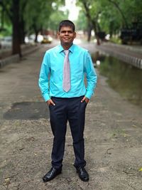 Portrait of young businessman standing on footpath