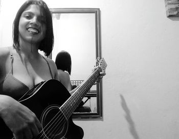 Portrait of smiling woman playing guitar at home