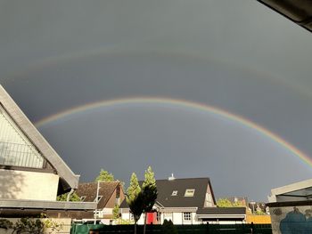 Low angle view of rainbow over buildings against sky