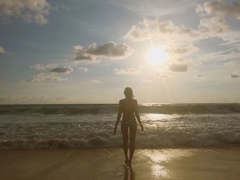 Rear view of man standing on beach against sky